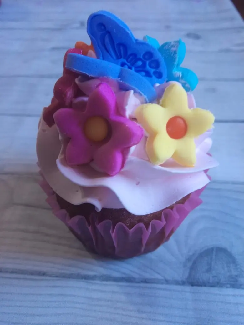 Cupcakes. cupcake decorado con flores y mariposas de fondant en colores rosa, amarillo y azul